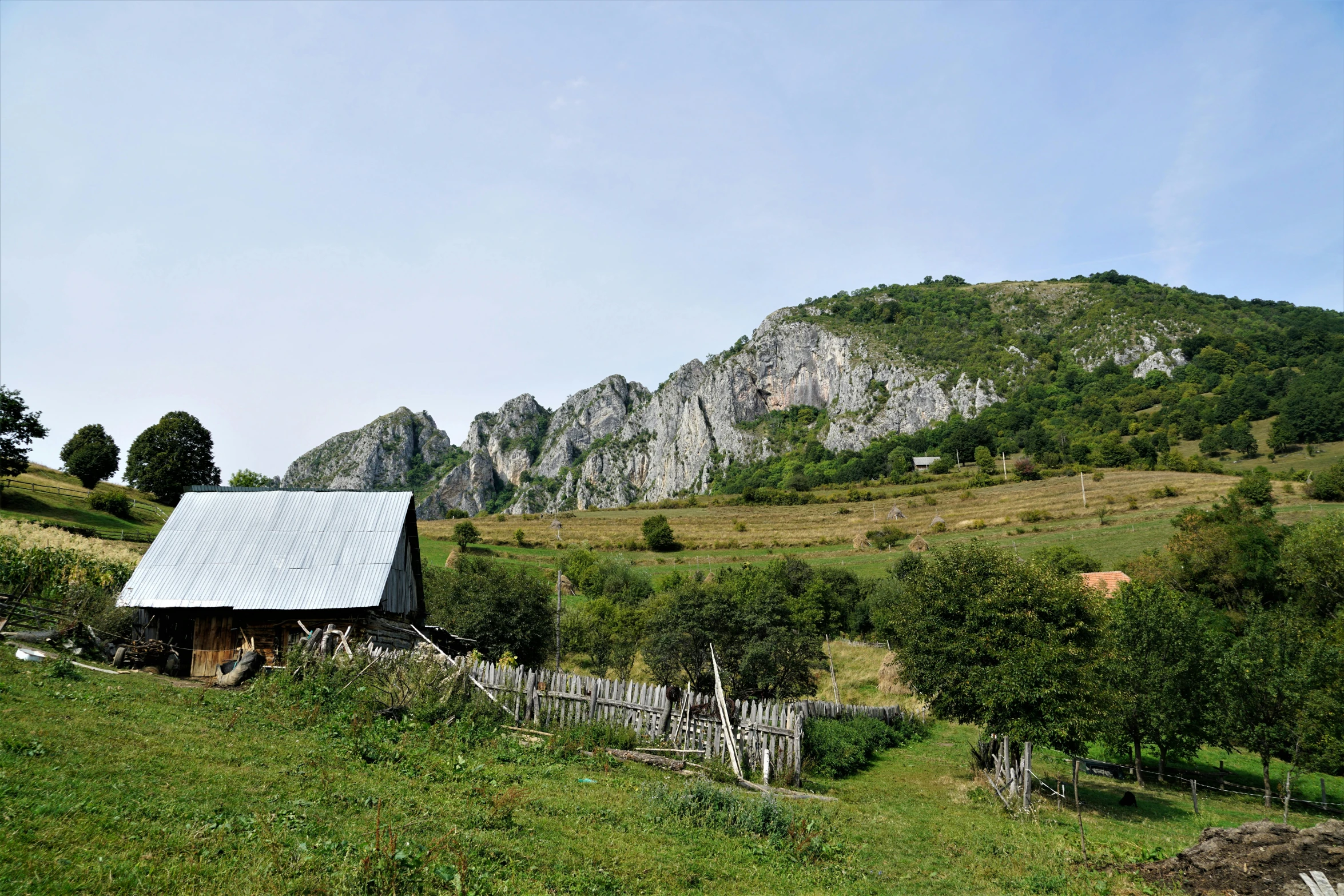 a barn sitting on top of a lush green hillside, by Muggur, pexels contest winner, romanian heritage, big sharp rock, seen from outside, slide show