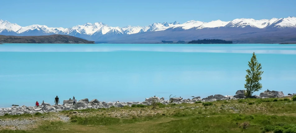 a large body of water with snow capped mountains in the background, by Charlotte Harding, pexels contest winner, hurufiyya, teals, new zeeland, cloudless blue sky, near a lake