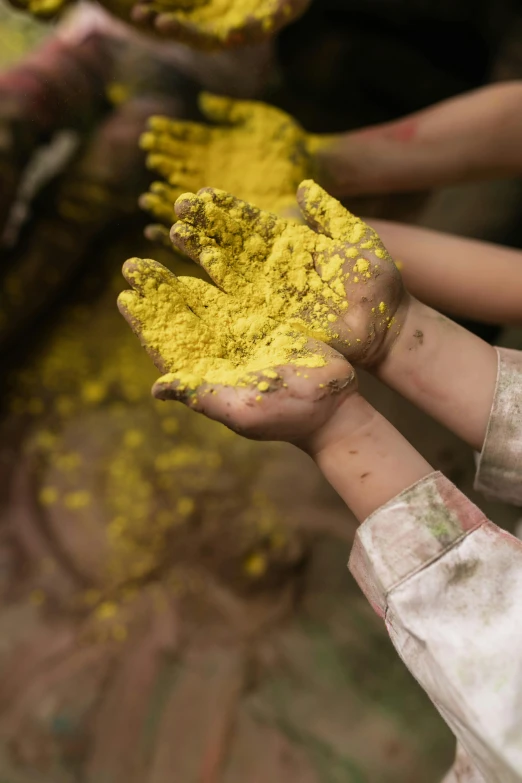 a group of people holding yellow powder in their hands, inspired by Steve McCurry, dry dirt, lush, up close, kids