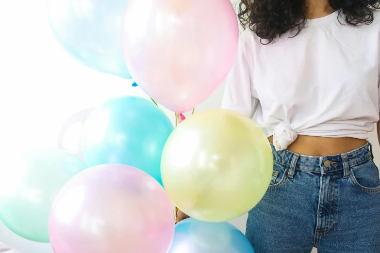 a woman standing in front of a bunch of balloons, by Rachel Reckitt, trending on unsplash, pale pastel colours, at a birthday party, closeup of arms, glossy finish