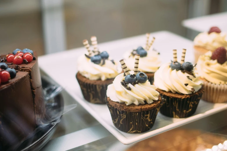 a display case filled with cupcakes and cakes, by Emma Andijewska, trending on unsplash, figuration libre, blueberries on the side, closeup at the food, manuka, brown