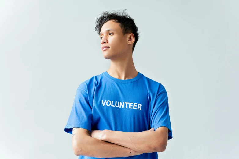 a man standing with his arms crossed wearing a volunteer t - shirt, trending on unsplash, ((blue)), 千 葉 雄 大, official product photo, virgil abloh
