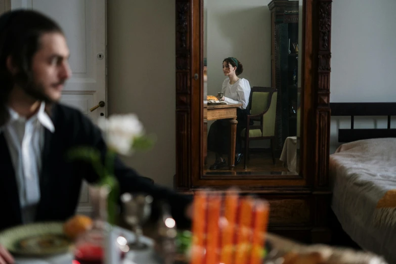 a man sitting at a table in front of a mirror, a still life, inspired by Henri-Julien Dumont, pexels contest winner, scene from a dinner party, marina abramovic, female looking, behind the scenes photo