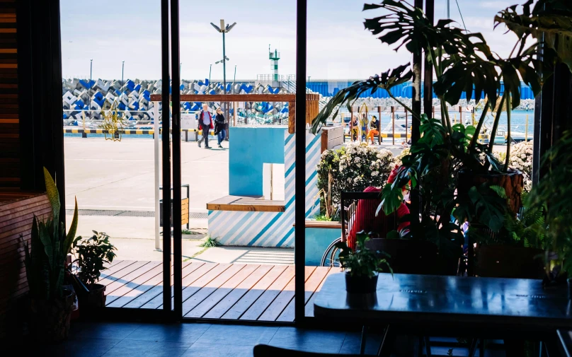 a view of a beach through a sliding glass door, by Julia Pishtar, happening, food court, caulfield, plants and patio, harbor