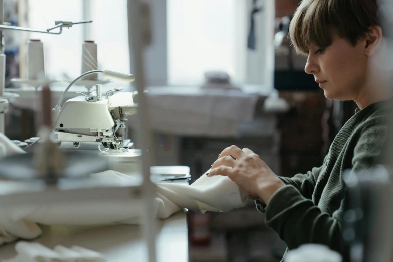 a woman working at a sewing machine in a factory, a portrait, inspired by Sarah Lucas, trending on unsplash, ignant, paul barson, weta workshop, premium quality