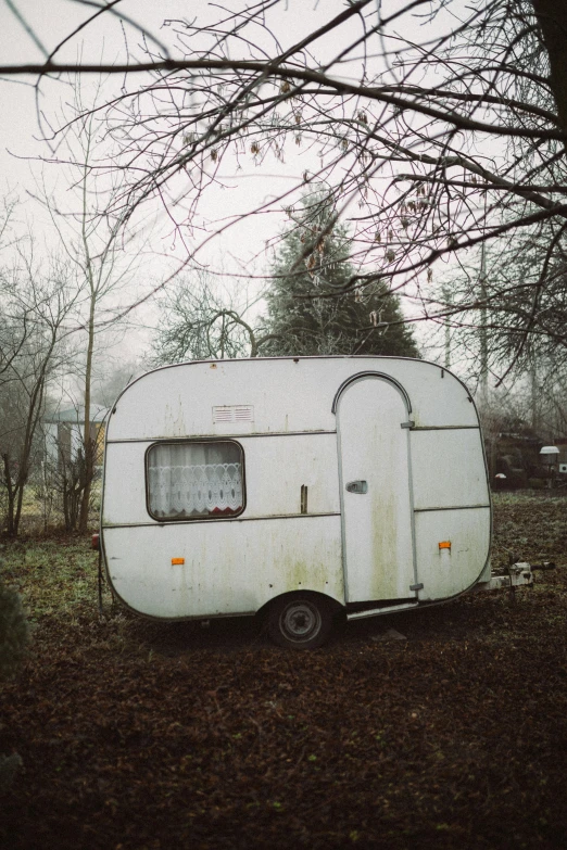 a white trailer sitting in the middle of a forest, an album cover, inspired by Elsa Bleda, unsplash, abandoned prague, gray sky, portapotty, in a suburban backyard