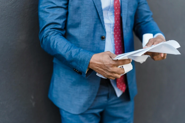 a man in a blue suit holding a piece of paper, by Daniel Lieske, pexels contest winner, multiple details, customers, advanced technology, instagram post