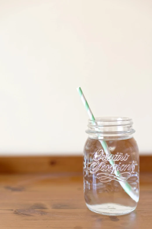 a mason jar sitting on top of a wooden table, a picture, with a straw, profile image