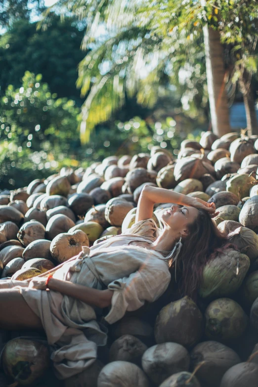 a woman laying on top of a pile of coconuts, unsplash, fine art, instagram picture, trending photo, full frame image, autumn