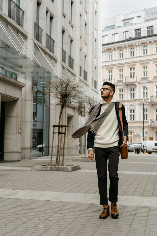 a man walking down a street next to tall buildings, pexels contest winner, wearing elegant casual clothes, jewish young man with glasses, muted colors. ue 5, inspect in inventory image