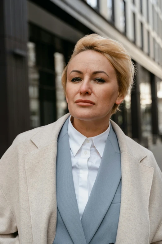 a woman standing on a sidewalk in front of a building, a portrait, trending on pexels, wearing wool suit, wearing white shirt, concerned expression, olga buzova