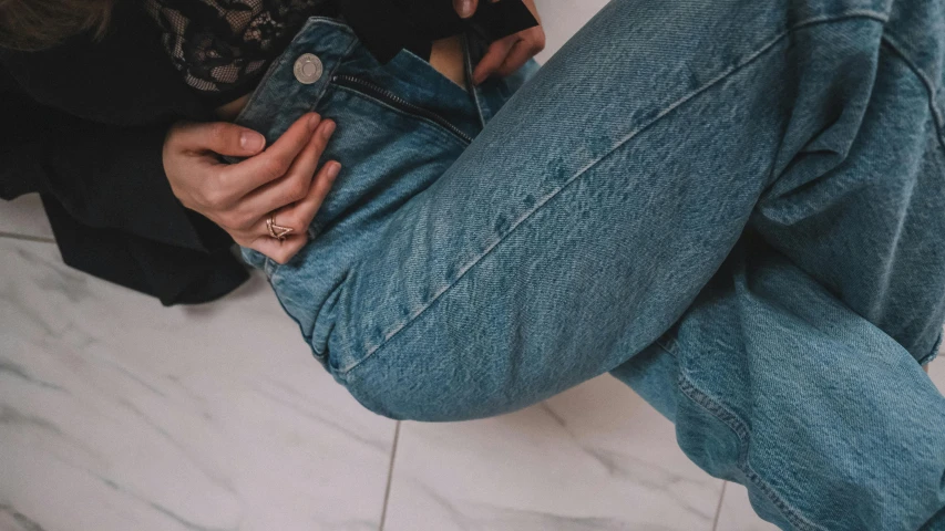 a close up of a person sitting on a toilet, trending on pexels, denim jeans, queer woman, stand on stone floor, her hand is on her waist