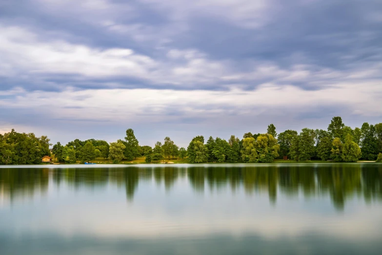 a body of water surrounded by trees under a cloudy sky, hannover, an amazing landscape image