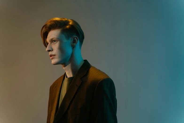 a close up of a person wearing a suit and tie, an album cover, by Emma Andijewska, pexels, bauhaus, red haired teen boy, on a mannequin. studio lighting, he is wearing a brown sweater, side profile waist up portrait