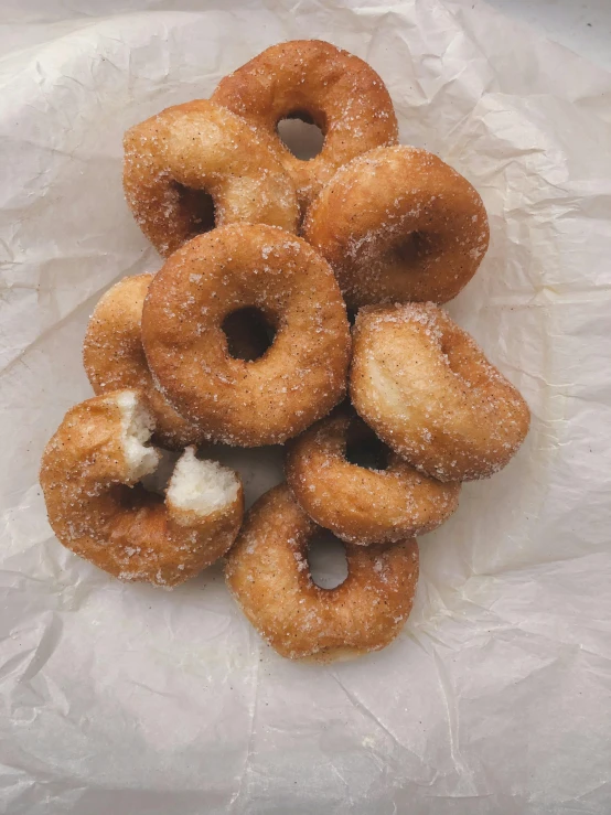 a pile of doughnuts sitting on top of a white paper, by Kristin Nelson, very crispy, ignant, square, with clothese