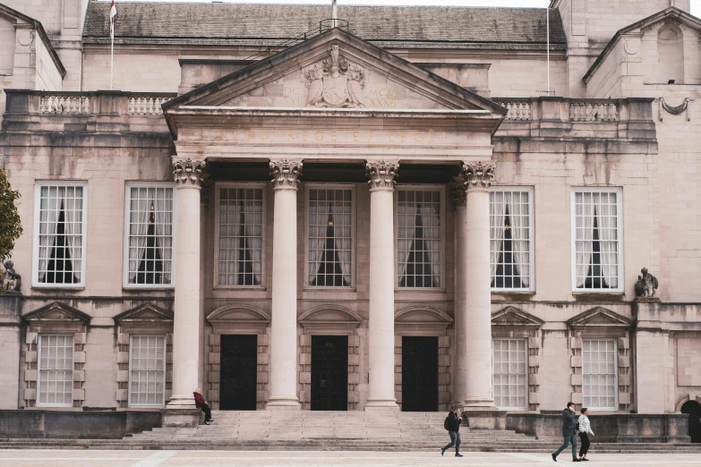 a couple of people that are standing in front of a building, inspired by Rachel Whiteread, pexels contest winner, neoclassicism, wales, official courthouse, thumbnail, overwatch building