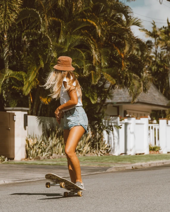 a woman riding a skateboard down a street, by Maggie Hamilton, unsplash contest winner, tropical style, tan shorts, sydney sweeney, lush surroundings