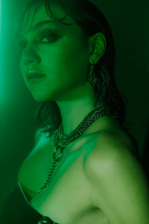 a woman standing in front of a green light, inspired by Elsa Bleda, renaissance, neck chains, smoky lighting, wearing spikes and piercings, highkey lighting