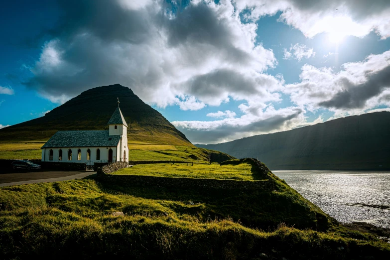 a church sitting on top of a lush green hillside, pexels contest winner, hurufiyya, faroe, late afternoon sun, youtube thumbnail, mountains and oceans