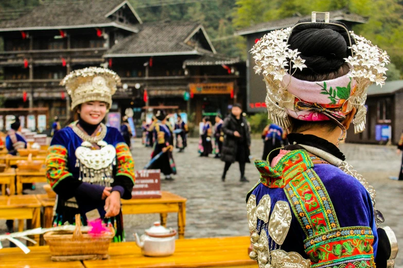 a couple of women standing next to each other, inspired by Miao Fu, pexels contest winner, on a village, elaborately costumed, panoramic view of girl, a wooden