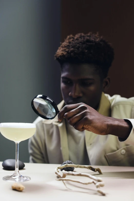 a man sitting at a table looking through a magnifying glass, a still life, inspired by François Bocion, trending on unsplash, people drink cocktails, man is with black skin, ignant, perfectly lit. movie still