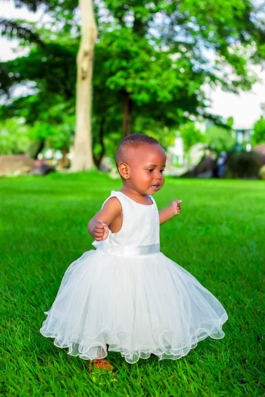 a little girl in a white dress standing in the grass, an album cover, by Chinwe Chukwuogo-Roy, pexels, 15081959 21121991 01012000 4k, on the runway, around tree babies running, a handsome