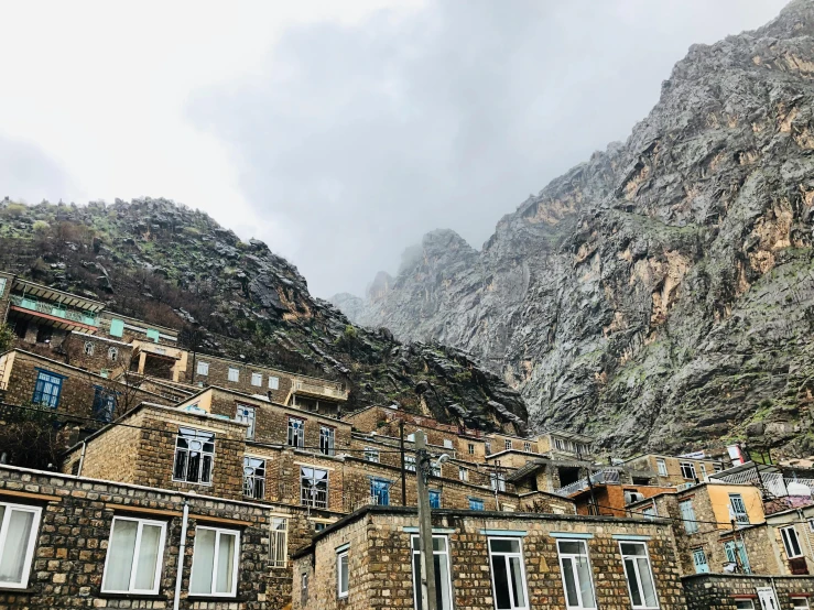 a group of buildings sitting on the side of a mountain, a picture, by Muggur, slight overcast weather, craggy, aykut aydogdu, view from ground