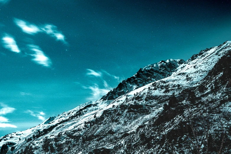 a mountain covered in snow under a blue sky, an album cover, pexels contest winner, hurufiyya, nighttime photography, black and cyan color scheme, quixel textures, on a canva