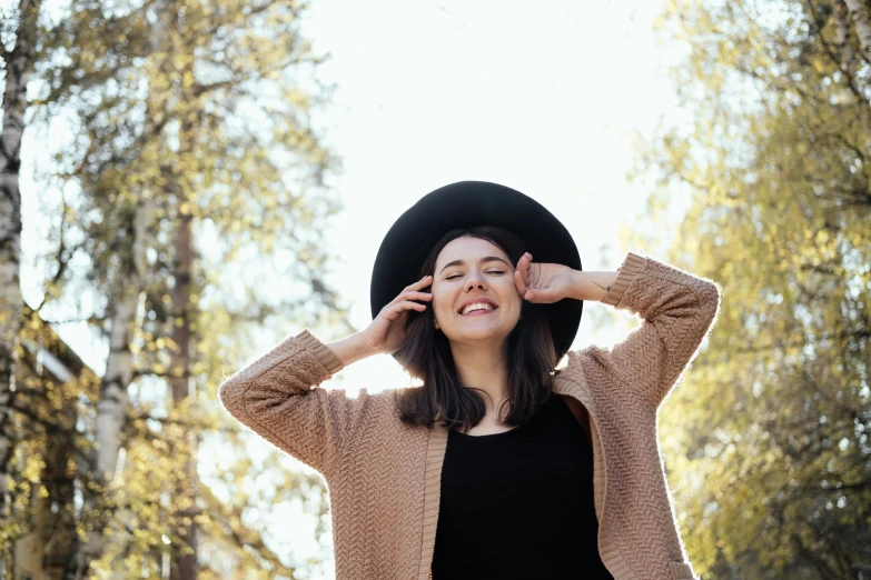 a woman in a hat is posing for a picture, pexels contest winner, wearing a cardigan, she is in pure bliss, pokimane, wearing a brown