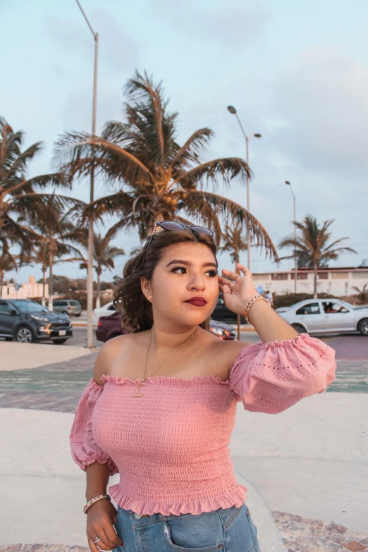 a woman standing on a sidewalk talking on a cell phone, by reyna rochin, instagram, happening, in a beachfront environment, puff sleeves, mexican, ((pink))