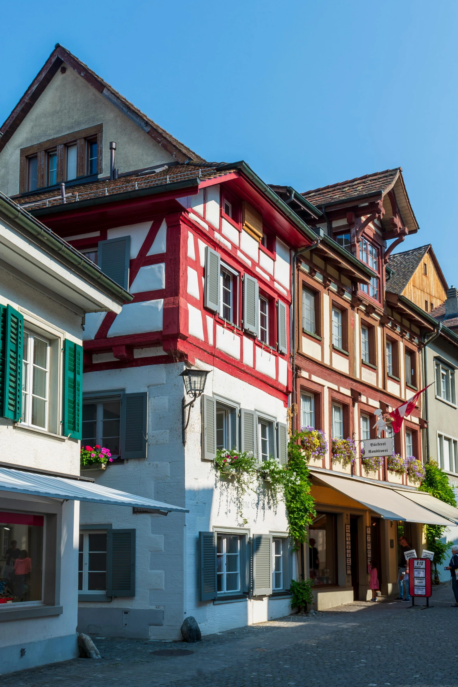 a couple of buildings that are next to each other, inspired by Karl Stauffer-Bern, shutterstock contest winner, quaint village, bright summer day, square, red and white