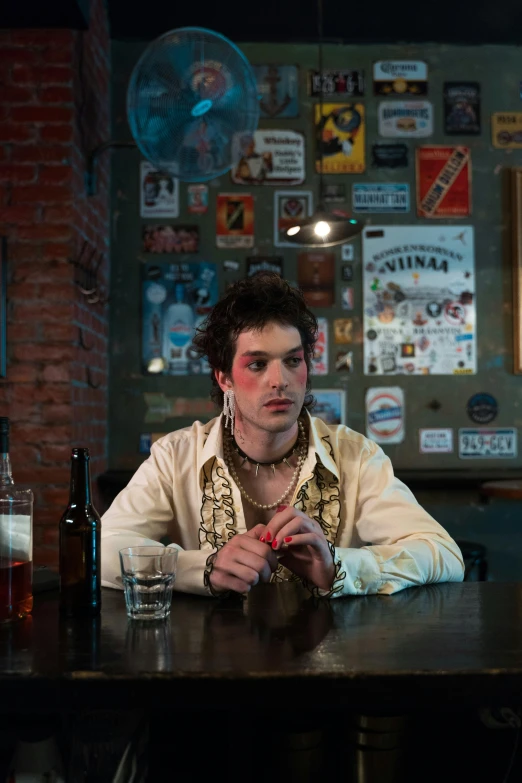 a man sitting at a table in a bar, an album cover, by Jacob Toorenvliet, featured on reddit, renaissance, lgbtq, still image from tv series, skins, whiskey