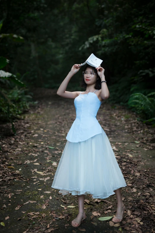 a woman in a white dress holding a paper star above her head, inspired by Alice Prin, blue corset, in serene forest setting, wearing a blue qipao dress, wearing organza gown