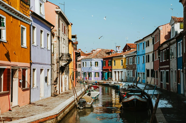 a canal filled with lots of boats next to tall buildings, inspired by Quirizio di Giovanni da Murano, pexels contest winner, colorful house, quaint village, conde nast traveler photo, lo - fi colors