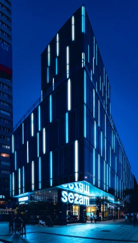a very tall building sitting in the middle of a city, inspired by Emanuel Schongut, blue accent lighting, award winning shopfront design, accent lighting : : peugot onyx, university