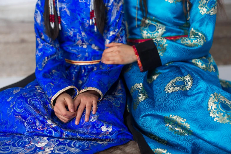 a couple of women sitting next to each other, trending on unsplash, cloisonnism, blue clothing, medium closeup shot, mongolia, anthropology photo”