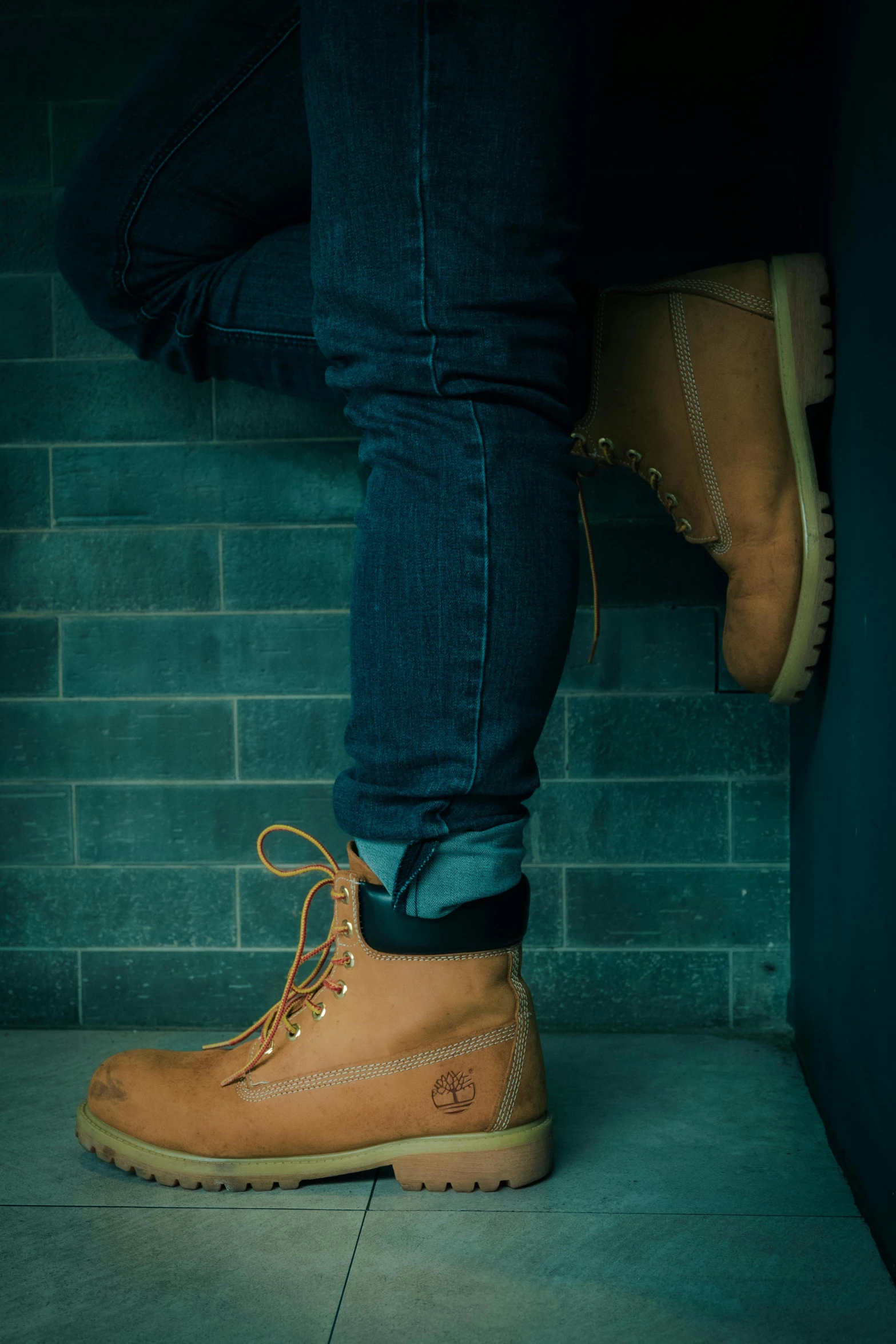 a person standing in front of a brick wall, inspired by Elsa Bleda, trending on pexels, photorealism, he has boots, lumberjack, worksafe. instagram photo, sitting