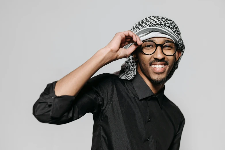 a close up of a person wearing a hat and glasses, inspired by Sheikh Hamdullah, trending on pexels, hurufiyya, dramatic smiling pose, somali attire, in an action pose, a handsome