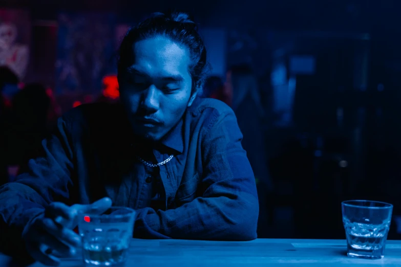 a man sitting at a table with a glass of water, a portrait, inspired by Liam Wong, pexels contest winner, chillin at the club together, perfectly lit. movie still, sakuga mad gunplay, blue mood