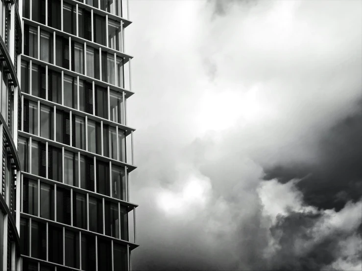 a black and white photo of a tall building, a black and white photo, by Karl Buesgen, clouds outside the windows, windows and walls :5, contrasting, cloud