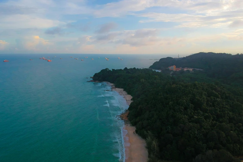 a large body of water next to a lush green hillside, pexels contest winner, singapore, airplanes bombing the beach, drone footage, panorama