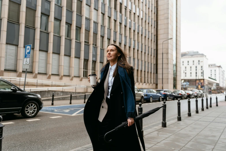 a woman walking down the street with a suitcase, by Emma Andijewska, pexels contest winner, he is wearing a black trenchcoat, woman holding recurve bow, in a business suit, woman drinking coffee