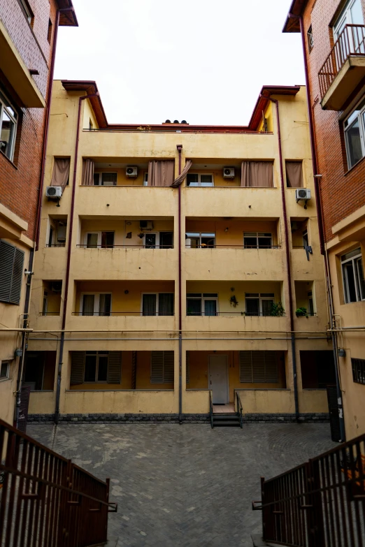 a couple of buildings that are next to each other, inside an old apartment, post - soviet courtyard, crenellated balconies, some red and yellow