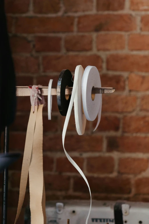 a tape dispenser in front of a brick wall, by David Simpson, unsplash, process art, wooden supports, white belt, fabrics, detail studio quality lighting