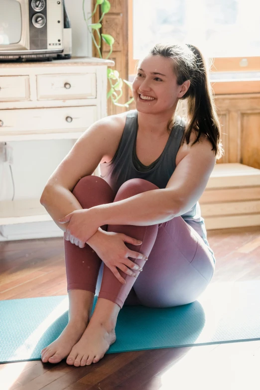 a woman sitting on top of a yoga mat, by Rachel Reckitt, happening, smiling, low quality photo, profile image, promo image