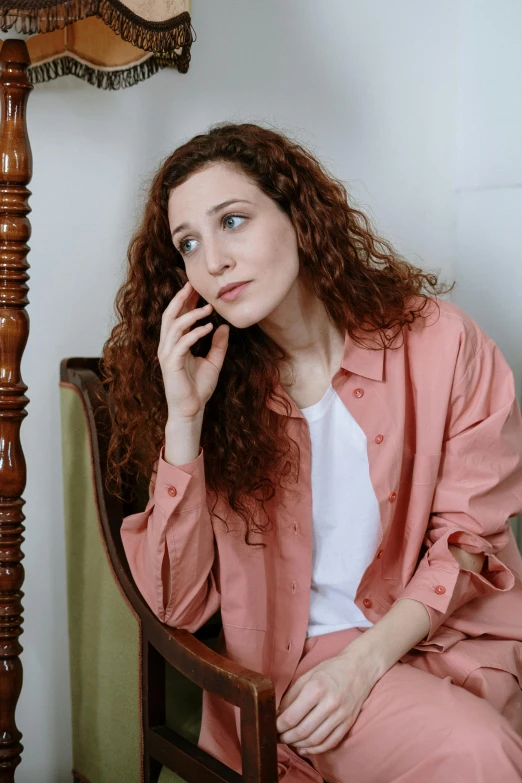 a woman sitting in a chair talking on a cell phone, a portrait, inspired by Anita Malfatti, trending on pexels, renaissance, coral brown hair, disappointed, curly haired, wearing casual clothes