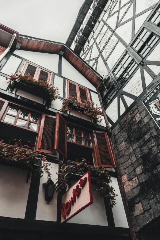 a very tall building with lots of windows, a photo, pexels contest winner, art nouveau, medieval tavern, flowers, red and white and black colors, unsplash photo contest winner