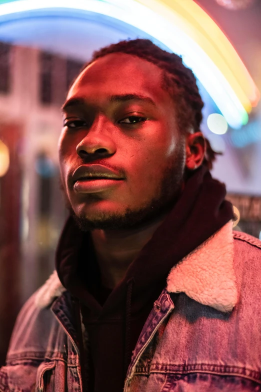 a man standing in front of a neon sign, an album cover, trending on pexels, brown skin, headshot portrait, (night), 2 4 - year - old man