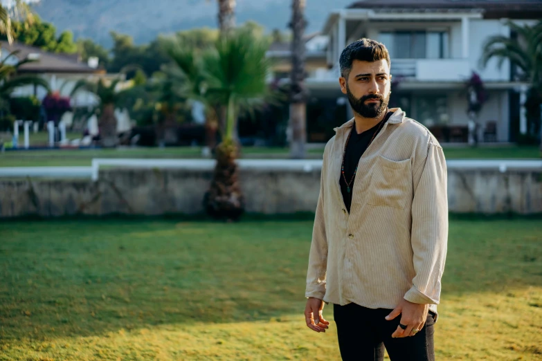 a man standing on top of a lush green field, an album cover, by Ismail Acar, pexels contest winner, hurufiyya, wearing a linen shirt, zayn malik, seaside, middle eastern