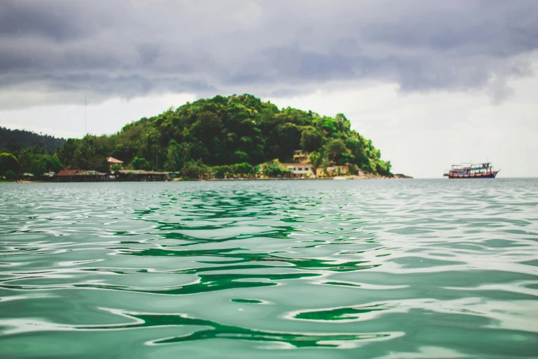 a small island in the middle of a body of water, by Emma Andijewska, unsplash, sumatraism, an elegant green, view from the sea, manly, wet climate